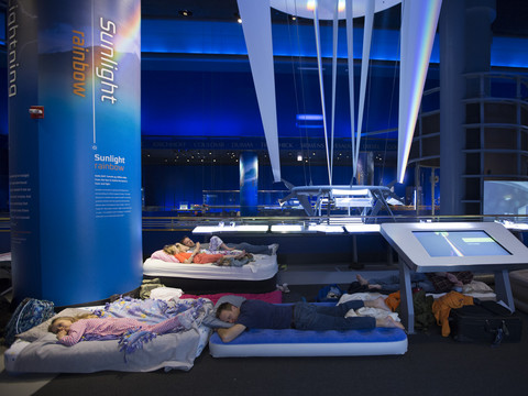 Snoozeum guests sleeping on air mattresses in the Science Storms exhibit.