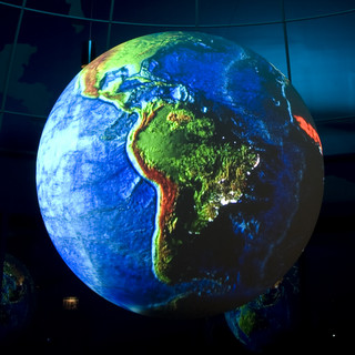 An image of the earth is projected onto a smaller globe floating in a large, globe-like dome.