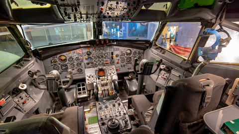 View from inside an airline cockpit looking at the controls and chairs