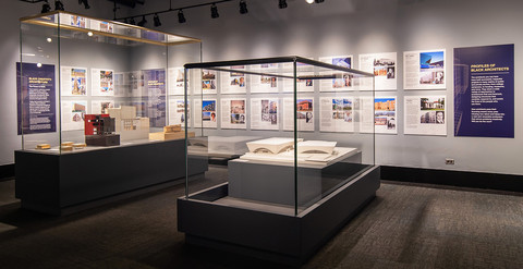 Display cases with books and panels from the Black Creativity Architecture Exhibit