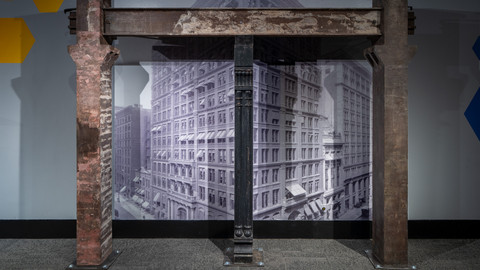 Steel beams from the Home Insurance Building in front of a photo of the building